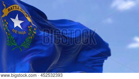 The Us State Flag Of Nevada Waving In The Wind. Nevada Is A State In The Western Region Of The Unite