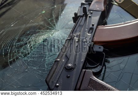 AKM(Avtomat Kalashnikova) version of Kalashnikov assault rifle and car wreck. April 7, 2022. Kiev Region, Ukraine