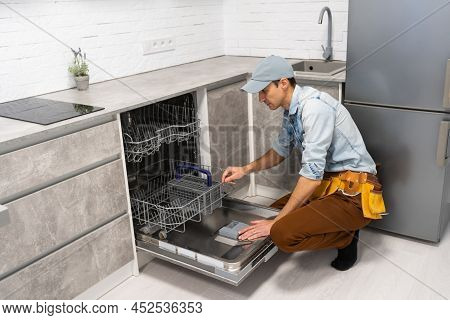 Man Opening Or Closing Dishwasher In The Kitchen.