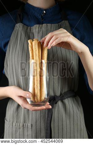 Woman Taking Fresh Delicious Grissino From Glass On Black Background, Closeup