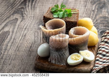 Homemade  Marinated Herring Roll With Rye Bread And Baby Potato With Quial Eggs On Wooden Table