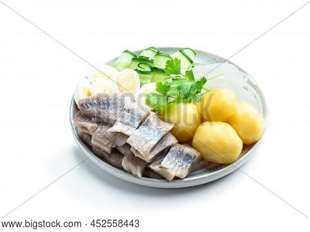 Salted  Herring With Boiled Potatoes And Quial Eggs On A White Plate Isolated On White