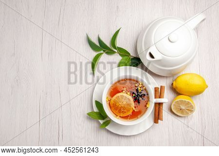 Top View Tea And Cinnamon A Cup Of Herbal Tea Cinnamon Sticks On The Saucer Lemon Teapot And Leaves 