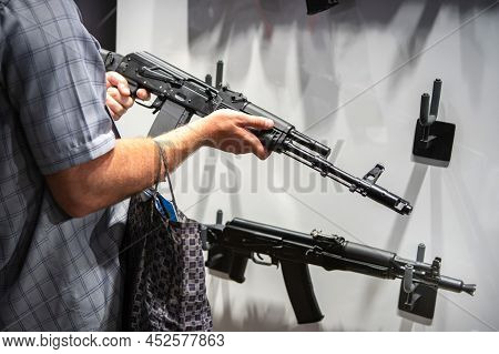 A Man In Civilian Clothes Examines Samples Of Firearms. Demonstration Of Modern Machine Guns For War