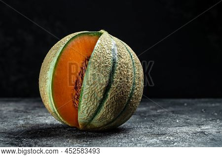 Raw Organic Tuscan Melon Cantaloupe. Yellow Pieces Of Melon On A Wooden Board On A Dark Background, 