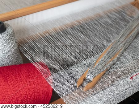 Handloom With Wooden Shuttle With Mottled Linen Thread And Two Bobbins Of Gray And Red Yarn