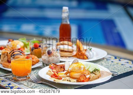 Breakfast At Hotel By The Pool. Table With Delicious Food By The Beautiful Blue Swimming Pool, Trave
