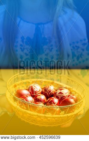 Defocus Ukrainian Girl In Vyshyvanka Holding Basket Of Colored Red Eggs On Nature Green Grass Backgr