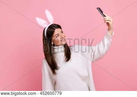 Side View Portrait Of Brunette Female With Bunny Ears Broadcasting Livestream Or Has Video Call, Wea