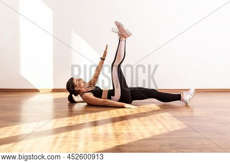 Sportive Female Raising Hand And Leg, Doing Crunches, Pumping Up Abdominal And Spine Muscles, Wearin