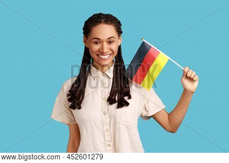 Portrait Of Pleasant Looking Woman With Black Dreadlocks Holding Germany Flag, Celebrating Day Of Ge