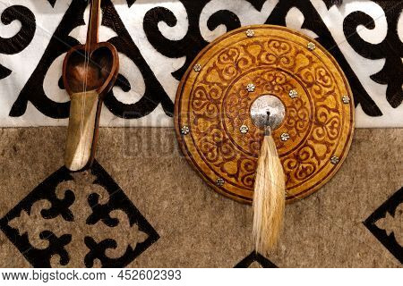 Kazakh Musical Instruments And Decorative Shield On The Background Of A Felt Carpet With National Pa