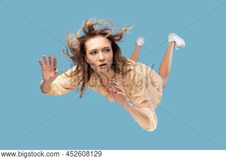 Beautiful Young Woman Levitating In Mid-air, Falling Down And Her Hair Messed Up Soaring From Wind, 
