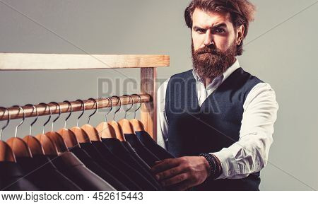 Man Suit, Tailor In His Workshop. Male Suits Hanging In A Row. Tailor, Tailoring. Stylish Mens Suit.