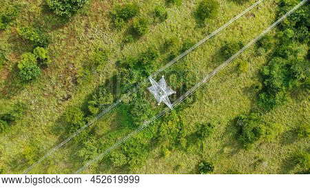 Aerial Top Down View High Voltage Steel Power Pylons In Green Field Countryside. Flight Over Power T