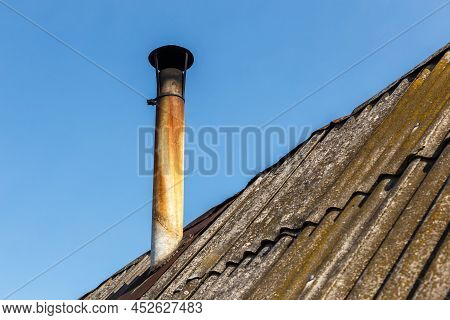 Chimney Pipe On The Roof Of The House Against The Blue Sky.