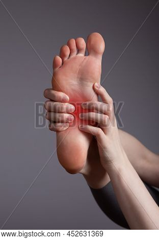 Foot Pain In Arch. Woman Holding Leg With Red Point Closeup. Plantar Fasciitis, Inflammation, Injuri