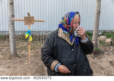 Bucha, Ukraine. Local Woman Near The Grave Of Her Relatives