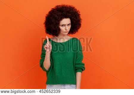 Portrait Of Serious Woman With Afro Hairstyle Wearing Green Casual Style Sweater Looking At Camera, 