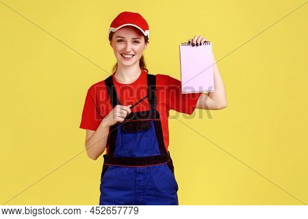 Portrait Of Satisfied Delighted Handy Woman Standing And Pointing At Paper Notebook, Smiling To Came