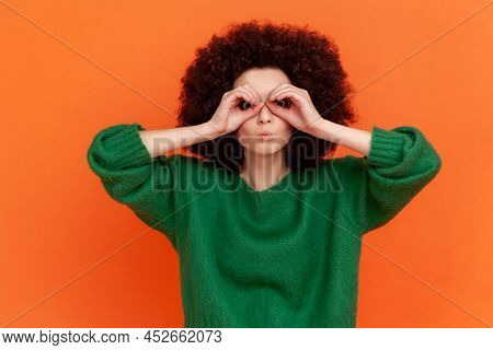 Funny Woman With Afro Hairstyle Wearing Sweater Looking Through Fingers In Binoculars Gesture, Obser
