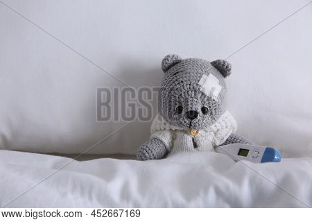 Cute Toy Bear With Sticking Plaster And Thermometer In Bed. Children's Hospital