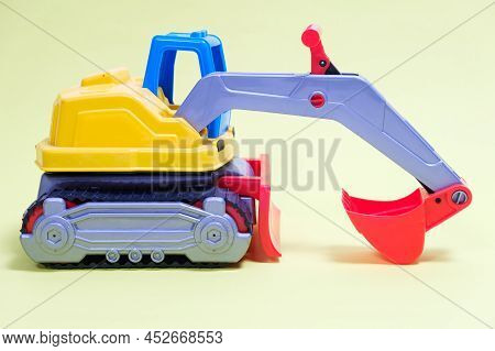 Plastic Excavator Car On Yellow Background. Construction Machinery Car For Digging For Toy Store And