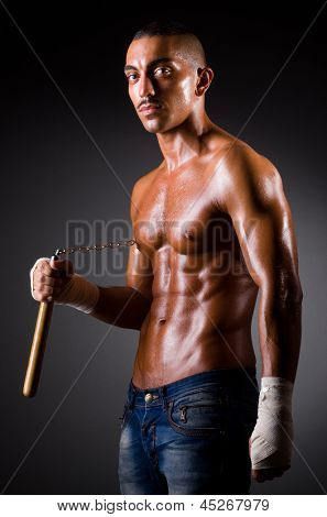 Muskuløs mand med nunchucks på hvid