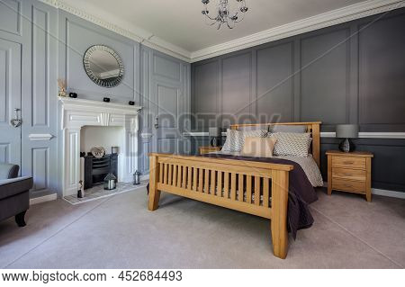 Fen Drayton, England - June 7 2018: Luxury Furnished Bedroom With Panelled Walls And Fireplace