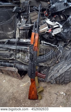 AKM(Avtomat Kalashnikova) version of Kalashnikov assault rifle and car wreck. April 7, 2022. Kiev Region, Ukraine