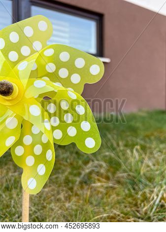 Yellow Pinwheel Outside With Houses In The Background