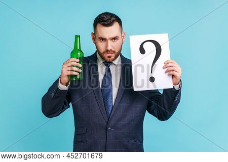 Drink Or Not. Portrait Of Serious Man With Beard Wearing Dark Official Style Suit Holding Bottle Wit