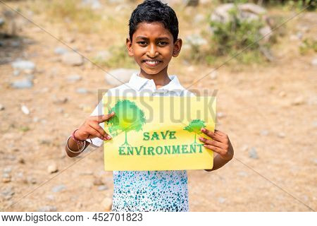 Smiling Teenger Boy Holding Save Environment Sign Board By Looking At Camera At Mountain - Concept O