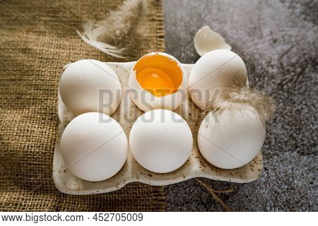 Fresh White Chicken Farm Eggs With Feathers In A Ceramic Box On A Brown Burlap Cloth Stand On A Gray