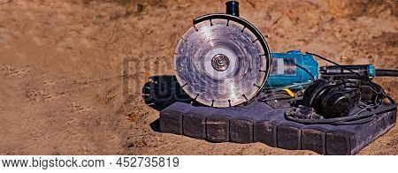 A Large Angular Grinder, With A Diamond Shield For Cutting Concrete, Along With Hearing Protection A