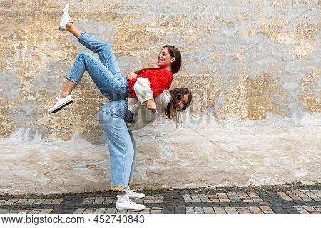 Funny Teenager Carrying Her Best Friend Piggyback On The Pavement At The Old Wall, Positive Emotions