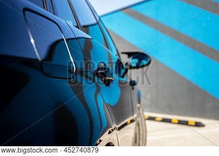 Side View Of A Mirror On A New Black Car.