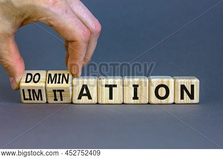 Domination Or Limitation Symbol. Businessman Turns Cubes, Changes The Word Domination To Limitation.