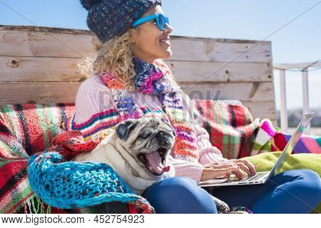 Woman Working On Laptop Computer Outdoor Sitting On A Wooden Bench With Her Best Friend Old Pug Dog.