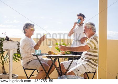 Mature And Young Family People Enjoy Time Together With Dirnks And Food Outdoor At Home - Concept Of