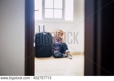 One Woman Sit Down Alone Inside Empty Home With Luggage - New House Mortgage Buyers People Concept -