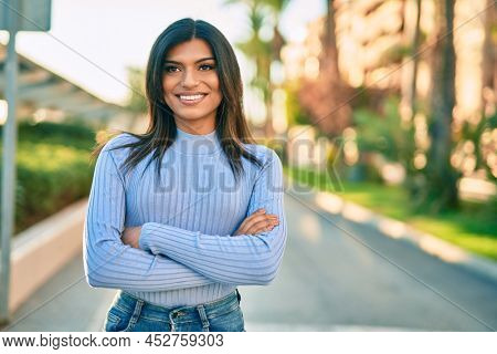 Beautiful hispanic woman smiling confient with crossed arms at the city