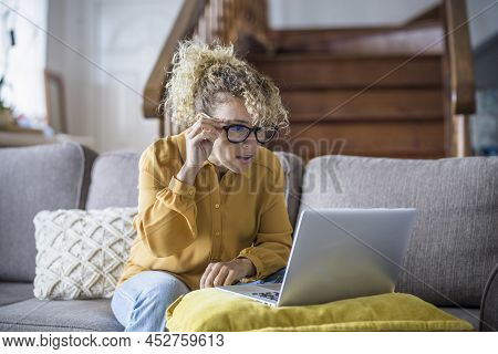 Surprised And Worried Adult Woman Reading Bad Notification On Laptop Computer At Home In Online Work