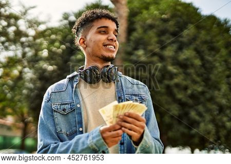 Hispanic young man holding 100 danish krone baknotes at the university campus