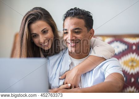 Young Interracial Couple Working Together With Laptop. People Lifestyle At Home Together Using Inter