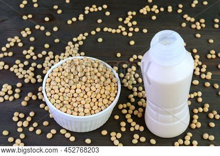 Bottle Of Soy Milk Isolated On Black Wooden Table With Scattered Soy Beans