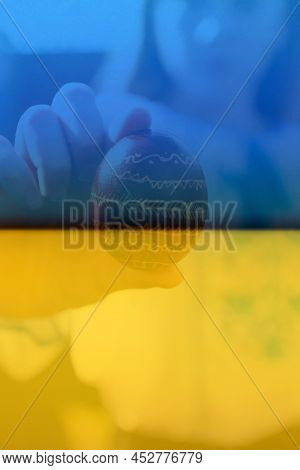 Defocus Ukrainian Girl In Vyshyvanka Holding One Colored Red Egg On Nature Background. Easter, Ukrai