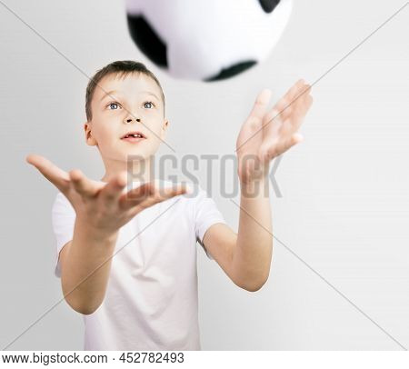 Portrait Of Boy Who Threw Soccer Ball. Child In A White T-shirt On Gray Background