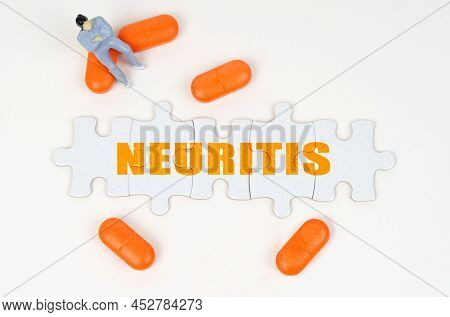 Medical Concept. On The White Surface Of The Tablet, A Miniature Human Figure And Puzzles With The I