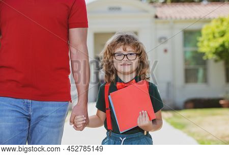 Portrait Of Happy Nerd Pupil Holding Teachers Hand. Father And Son Walking Trough School Park, Holdi